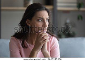 担心年轻的印度阿拉伯妇女坐在家里的沙发上看远处思考，焦虑、不开心、不开心、阿拉伯混血儿、女性患有精神心理、个人问题、哀悼或向往